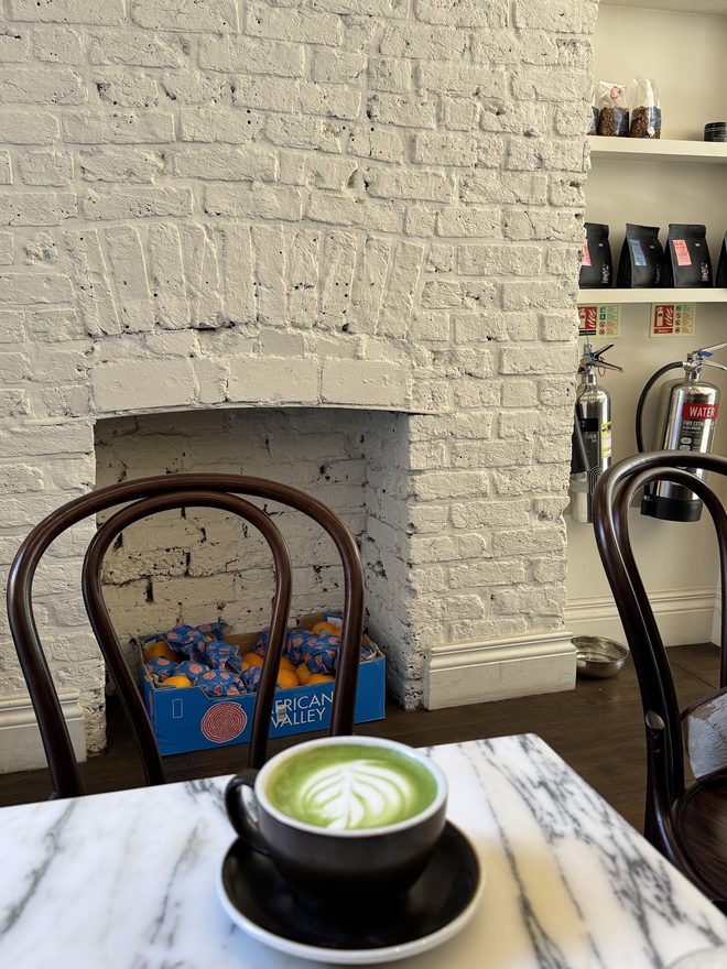 The whitewashed brick fireplace and shelves with a matcha latte on the table in front.