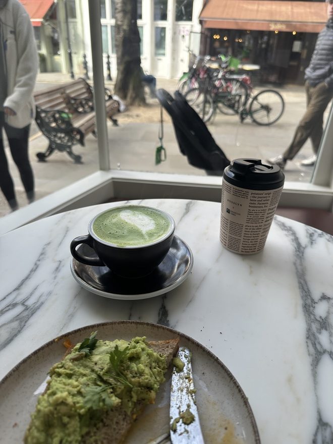 Matcha and toast on the window ledge with passers-by beyond the glass.