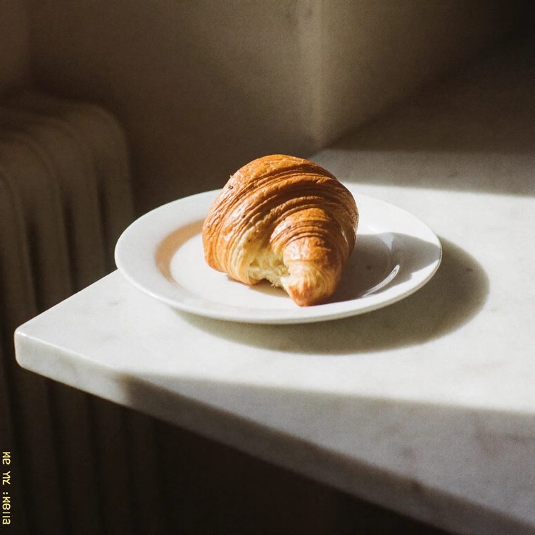 A butter croissant on a small plate.